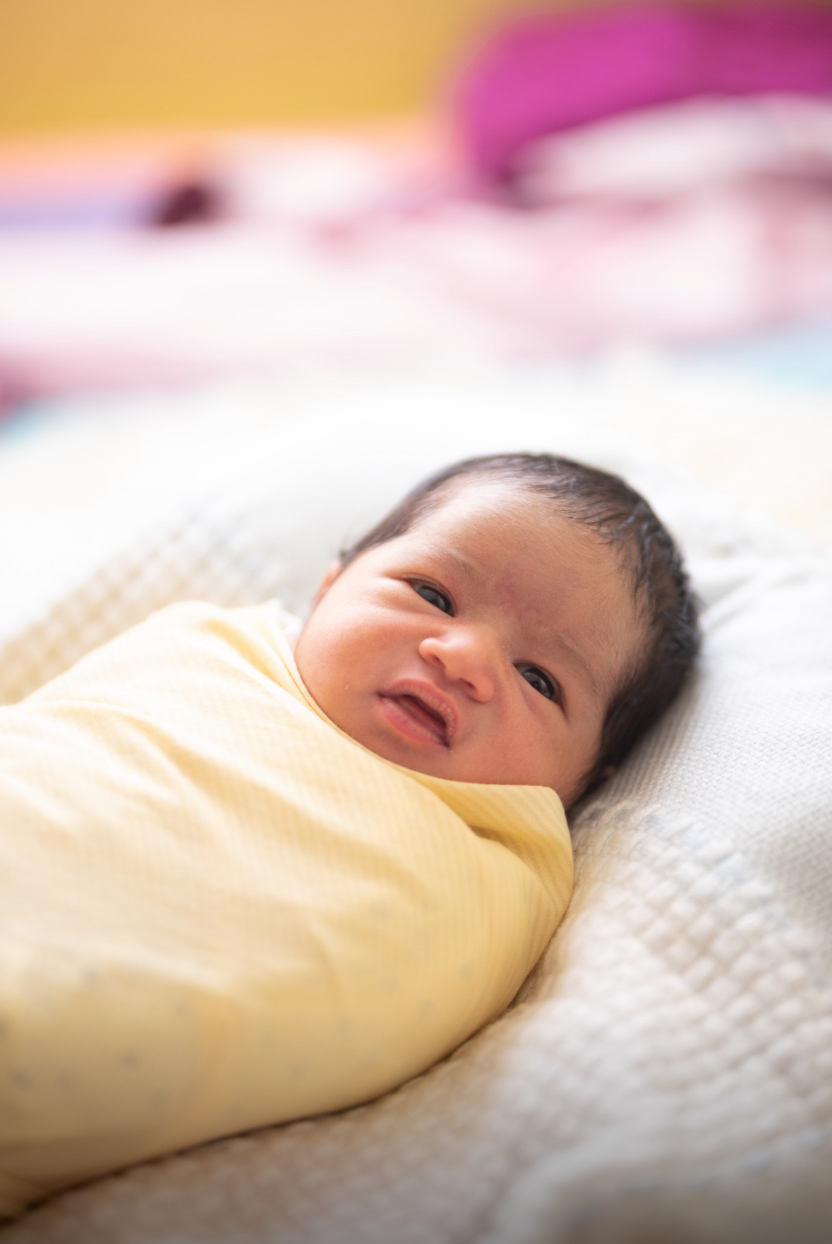 Nafisa as a newborn, swaddled in a yellow blanket